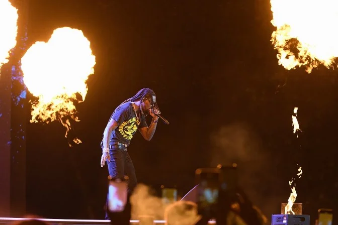 Offset performing live on stage with a microphone and fire effects at a 2024 music festival