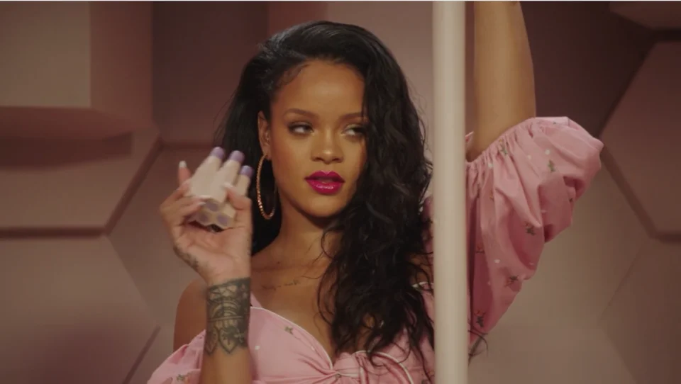 Rihanna holding a Fenty Beauty product during a promotional campaign.