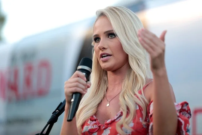 Tomi Lahren speaking with a microphone at an outdoor event
