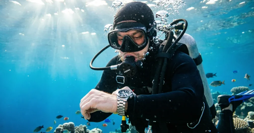 Diver checking wrist-mounted dive computer mid-dive underwater