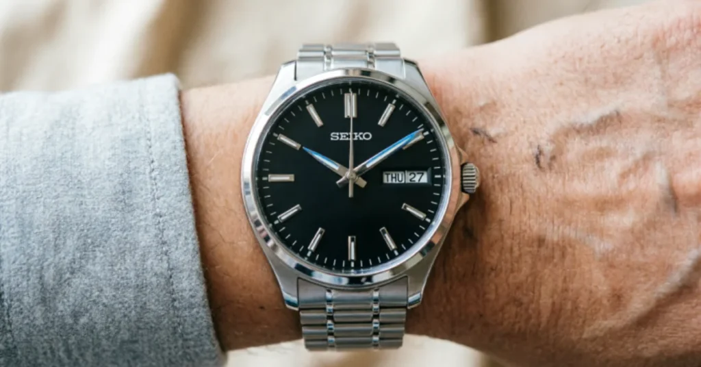 Seiko 5 Sports automatic watch wrist shot showing black dial and day-date display with steel bracelet