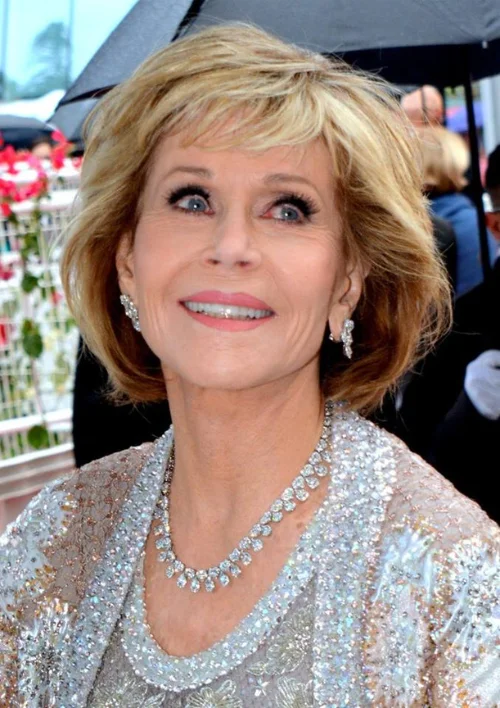 Jane Fonda, Ted Turner's third wife, smiling at a red-carpet event in a sequined gown and diamond necklace