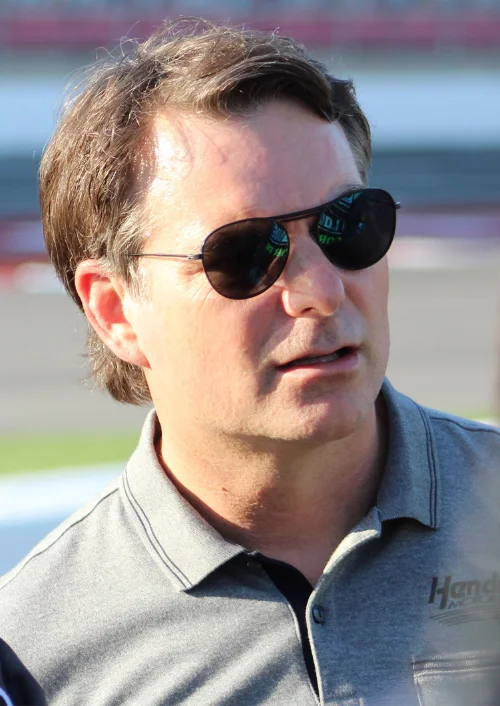 "Jeff Gordon post-racing career - NASCAR legend turned team executive at Hendrick Motorsports, wearing team-branded polo at racing event in 2026"