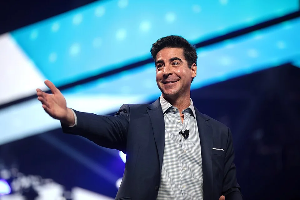 Jesse Watters gesturing on stage during a speaking appearance