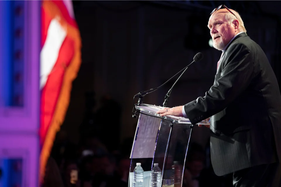"Terry Bradshaw at speaking engagement - NFL legend and Fox Sports analyst Terry Bradshaw in suit at podium, age 77, continuing his broadcasting and business career"