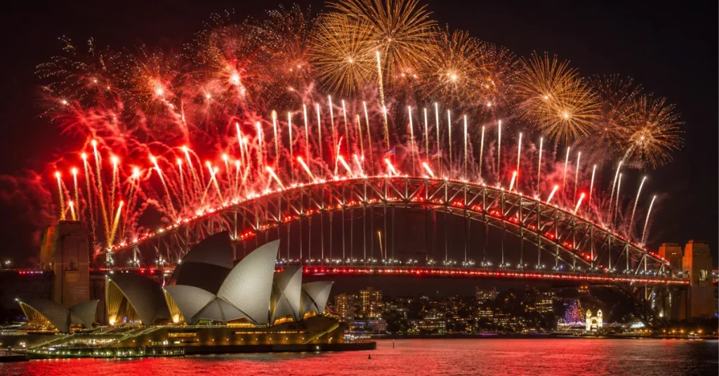 Best places to travel in December: Sydney Harbour Bridge and Opera House lit by red and gold midnight fireworks on New Year's Eve