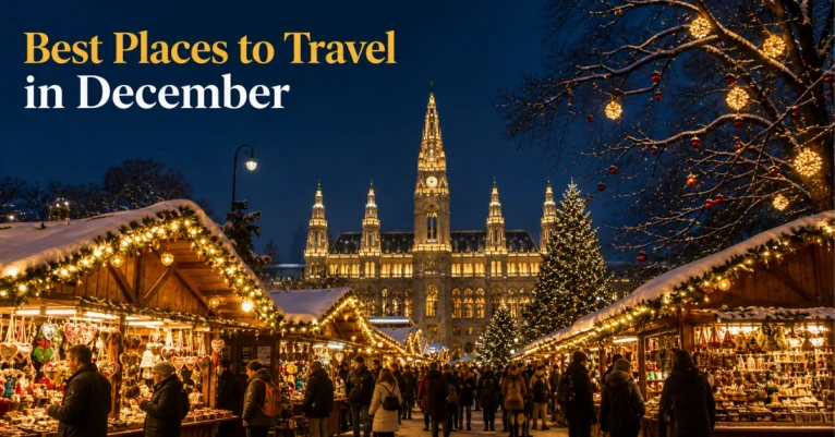 Best places to travel in December: Vienna's Christmas market at dusk with snow-dusted stalls, amber lights, and the illuminated Rathaus