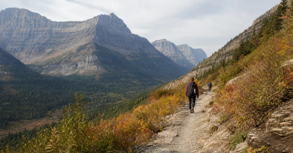 Best places to travel in September: two hikers on a quiet Glacier National Park trail with early autumn color and a vast valley view