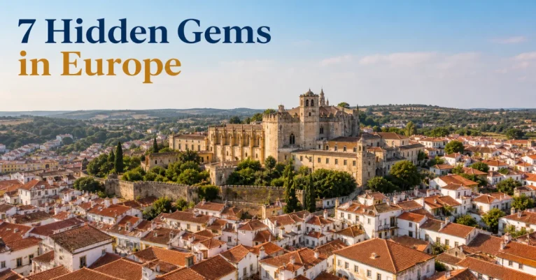 Hidden gems in Europe: Tomar's Convento de Cristo rising over a sea of terracotta rooftops in warm gold light