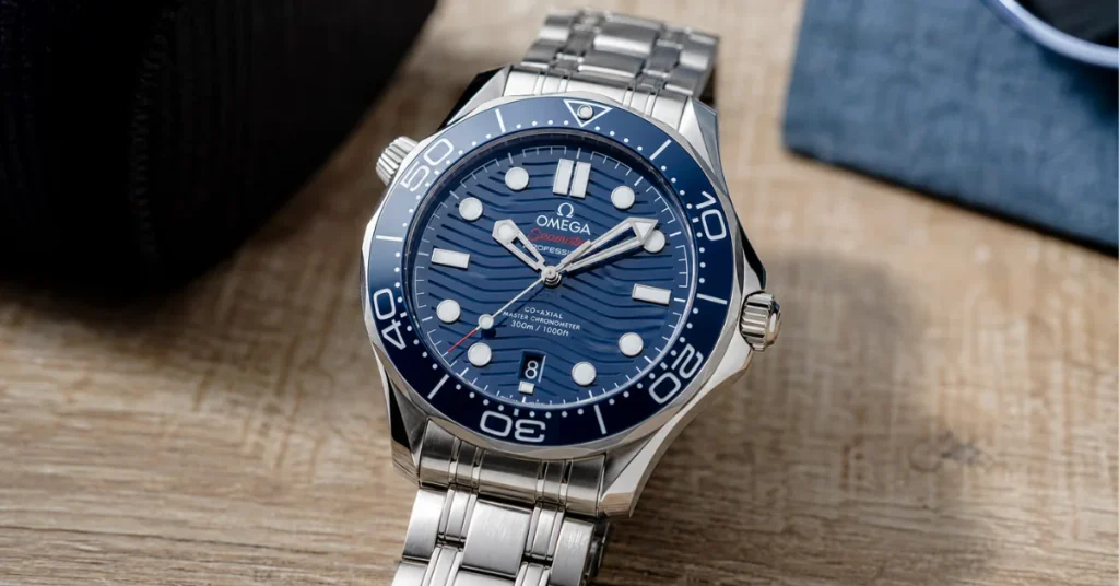 How much are Omega watches: an Omega Seamaster Diver 300M with a blue wave dial and ceramic bezel on a wooden table