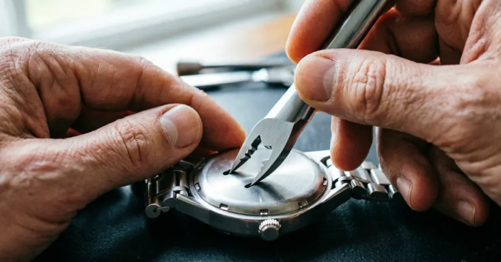 Seiko mod build: hands using a case-back wrench to open a watch case on a dark mat