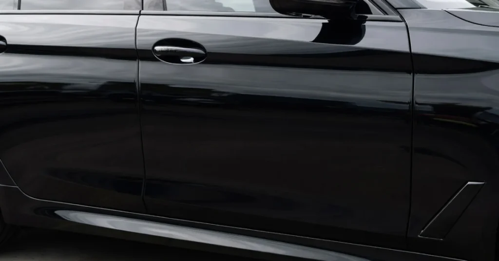 Glossy black sedan with a mirror-like finish reflecting golden-hour light, no visible scratches