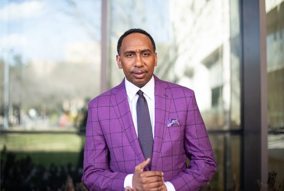 Stephen A. Smith in purple suit outside ESPN studios, commentator with $100 million contract