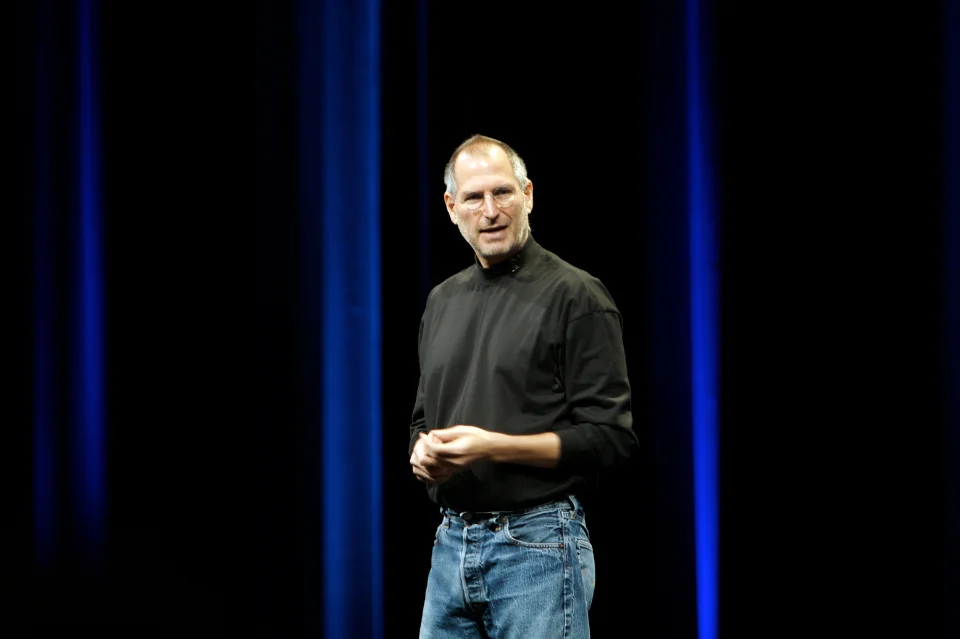 Steve Jobs on keynote stage in black turtleneck, Apple co-founder with $10-11 billion fortune