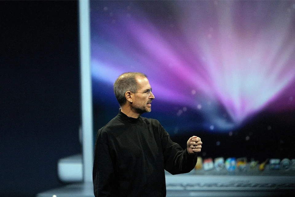 Steve Jobs gesturing on keynote stage, Apple co-founder with $10-11 billion fortune