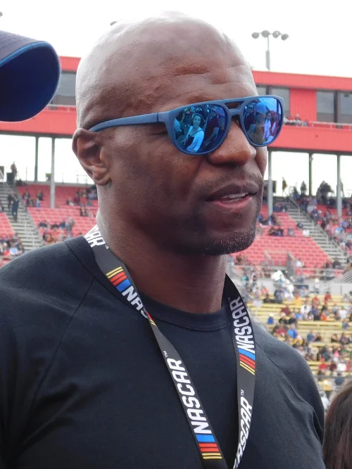 Terry Crews wearing reflective sunglasses at a stadium in 2017, two decades after his NFL retirement
