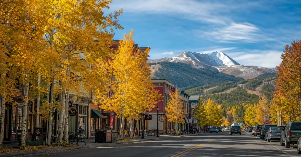 Best towns to visit in Colorado: Breckenridge's historic Main Street lined with golden aspen trees and snow-capped mountain backdrop in fall