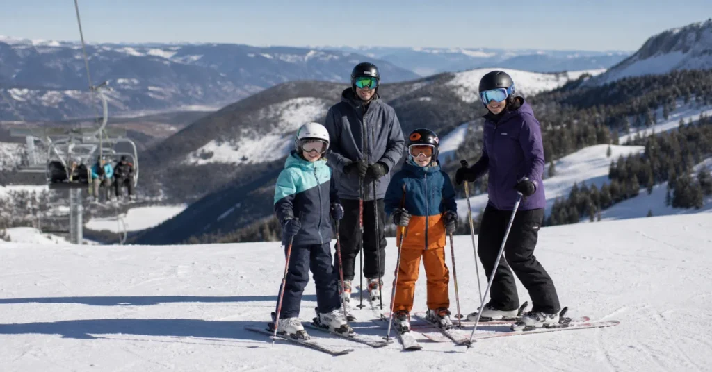 Most affordable ski resorts in the US: a family of four skiing together on an uncrowded slope with chairlift and mountains in the background