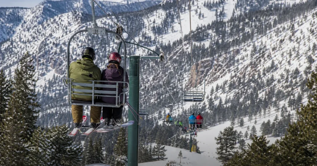 Most affordable ski resorts in the US: skiers on an older-style double chairlift at a community-run mountain with forested slopes