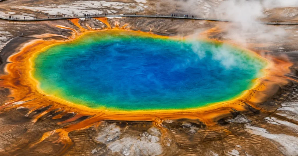 Most beautiful national parks in the US: an aerial of Yellowstone's Grand Prismatic Spring with its rainbow bacteria ring and boardwalk visitors
